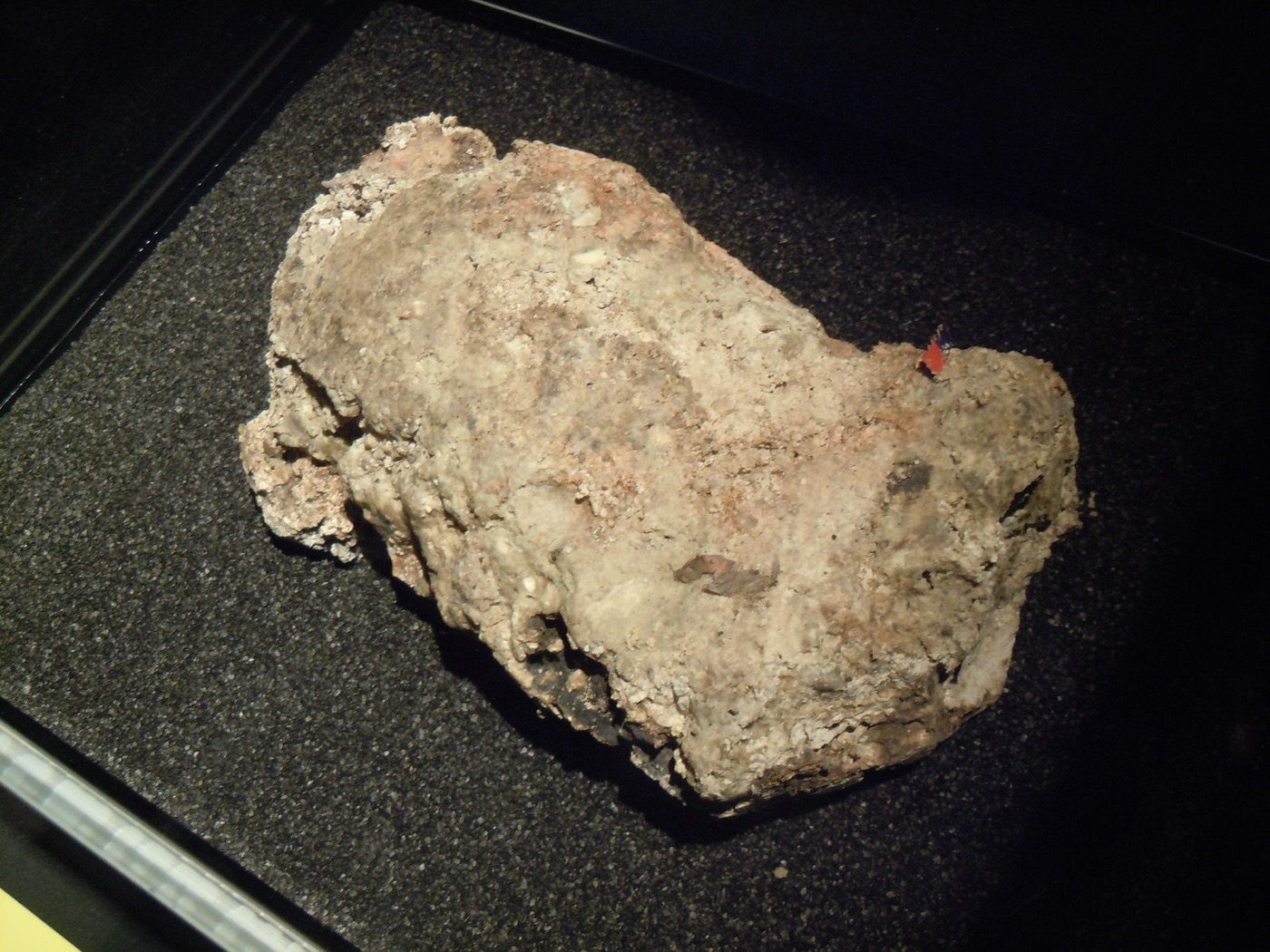 A piece of fatberg on display: fat, oil and wipes, set hard inside a sewer.
