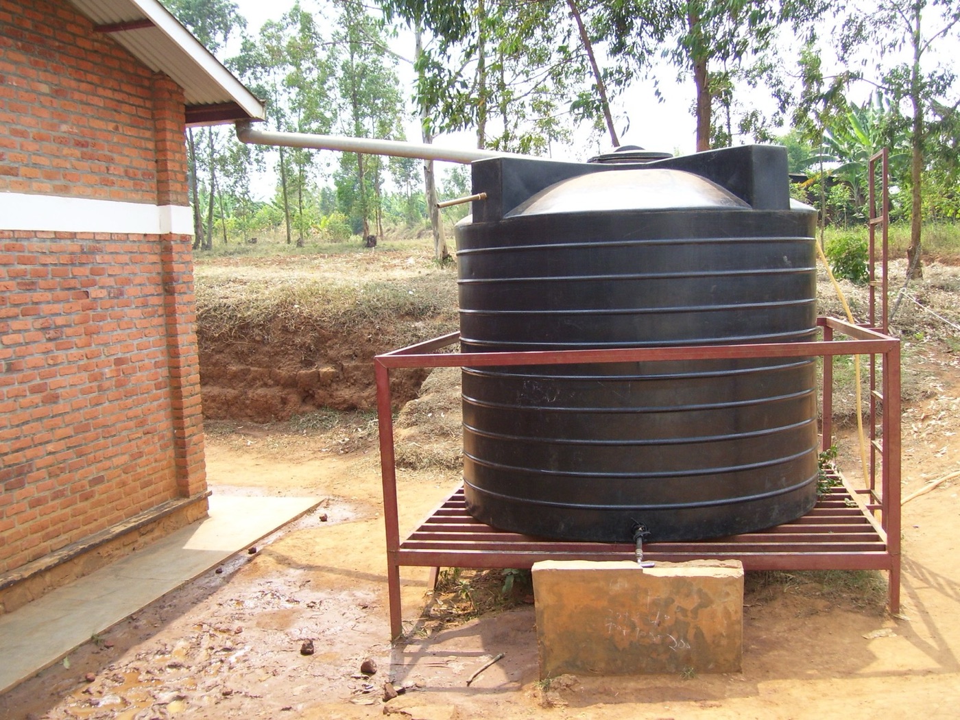 A rainwater tank on a stand. Sealed, dark and screened, the water keeps well.