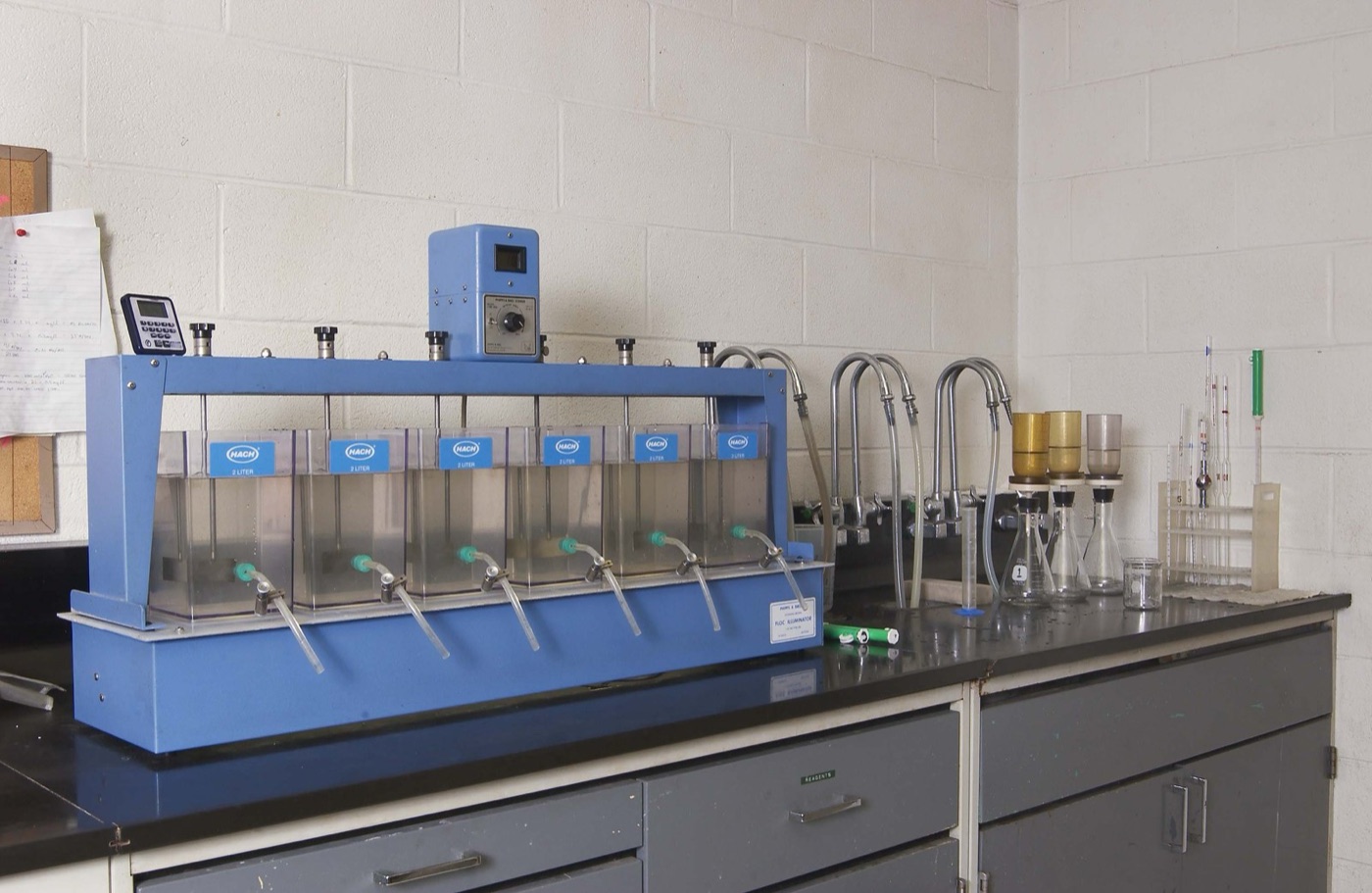The jar test: six beakers, six doses, and the operator watches which one clears first.