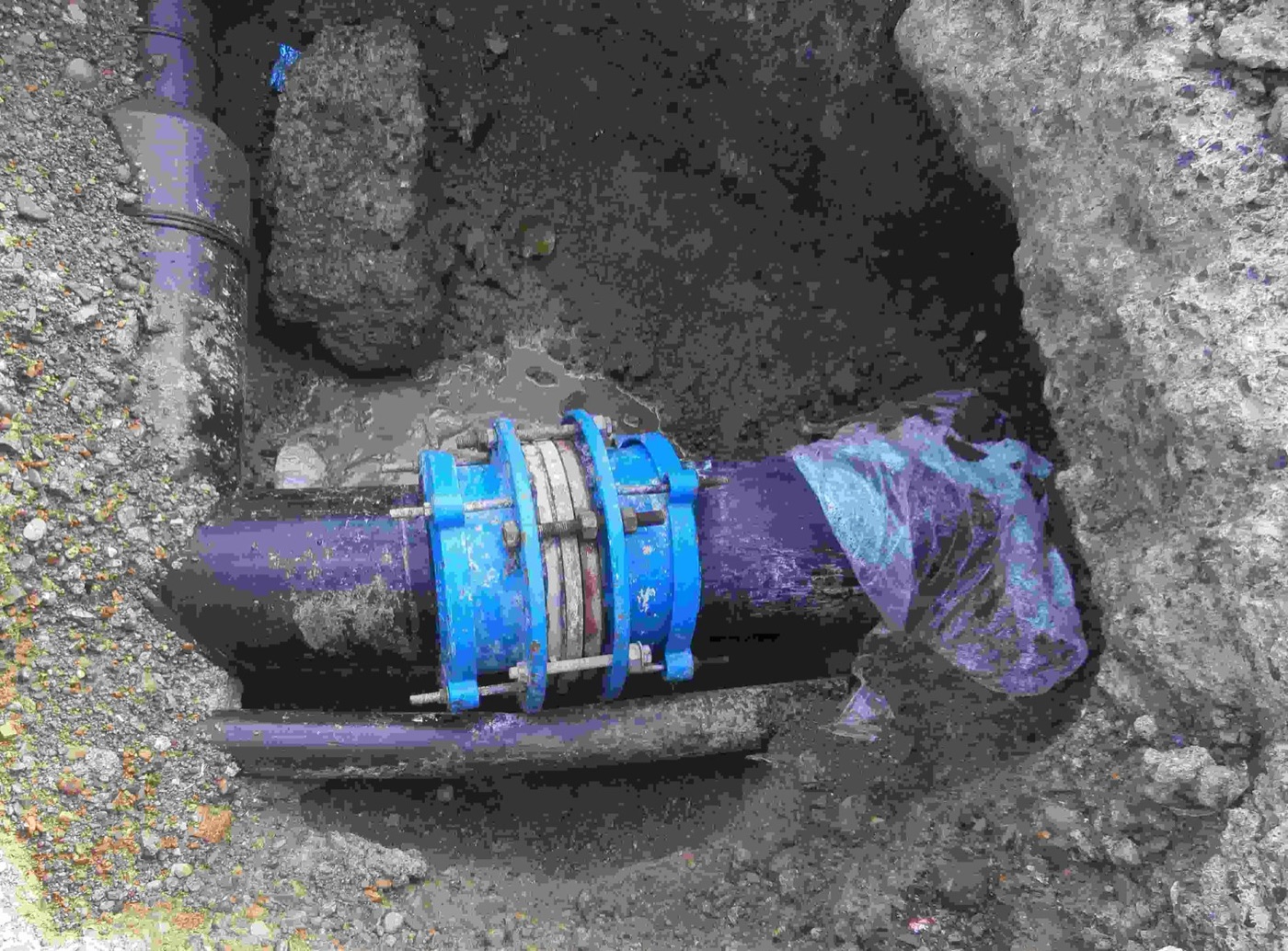 A repair clamp on a main in a trench. A leak found is a hole dug.