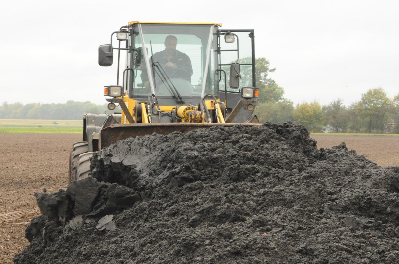 Dewatered sludge being moved by loader. Once it is a cake, it can be handled and trucked.