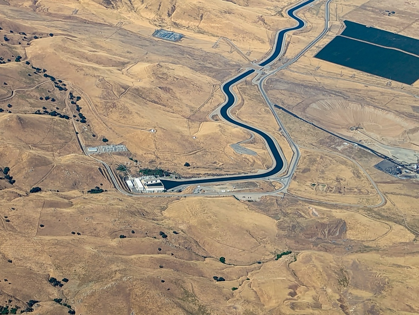 The California Aqueduct crossing the valley. In a wet year it carries the Sierra's snowmelt to the orchards; in a dry year the wells take over.