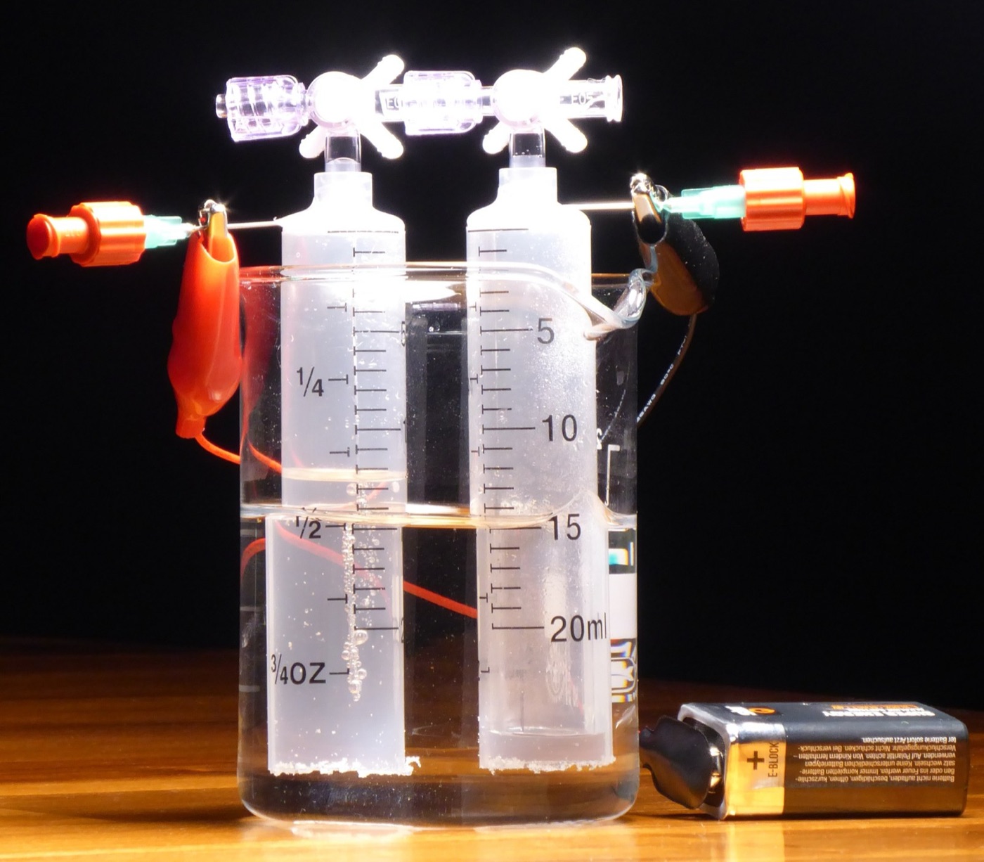 Electrolysis in a jar: hydrogen collects over one electrode, oxygen over the other, and nine litres of water make a kilogram of gas.