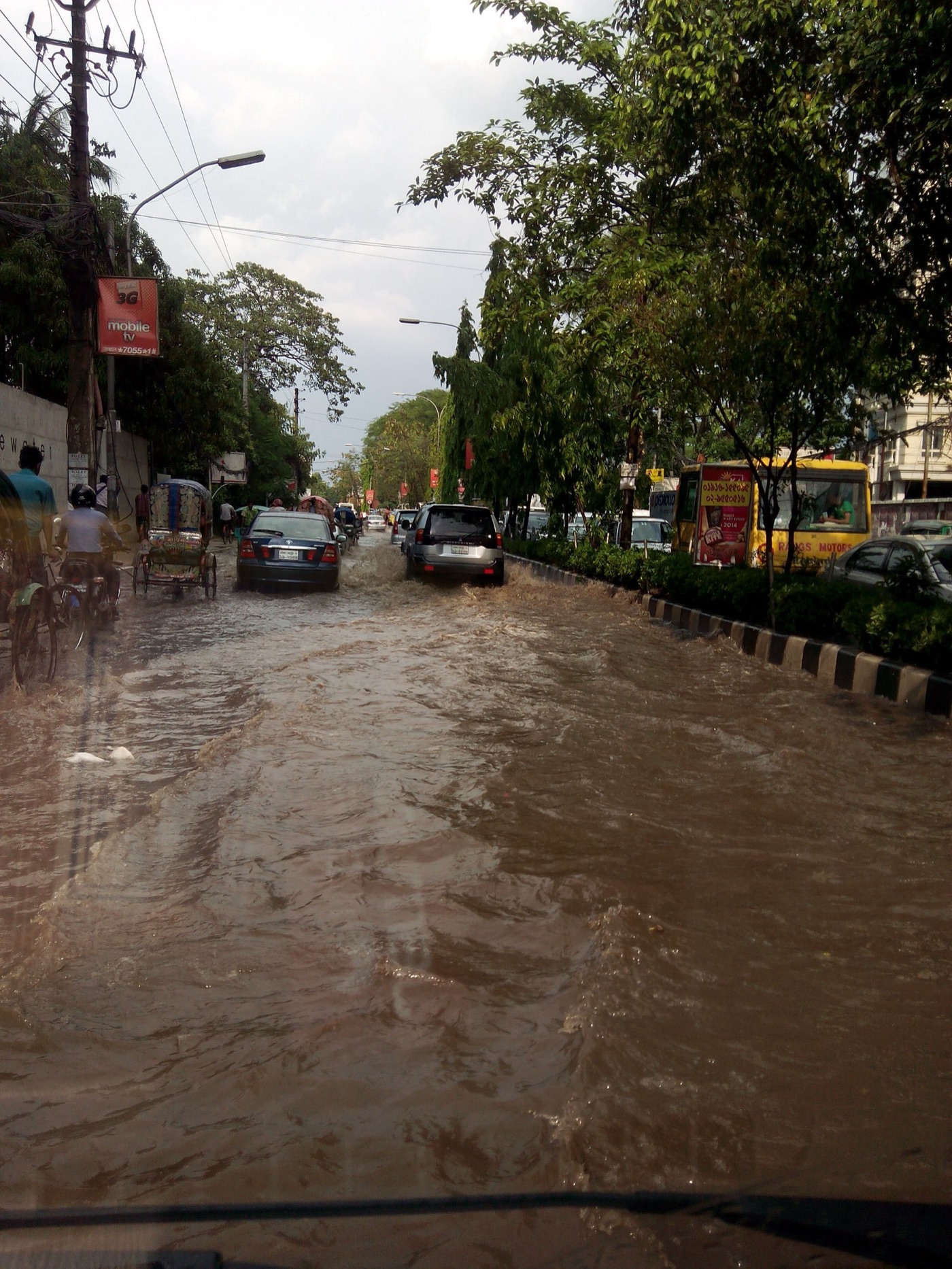 A Dhaka street after rain. The city floods in the wet season and drills in the dry one.